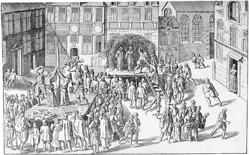 A historical engraving depicting a public execution by burning at the stake in a town square surrounded by tall, half-timbered buildings. On a raised wooden platform, several figures are bound to stakes while executioners prepare the kindling and a large crowd of townspeople and monks gathers to observe.