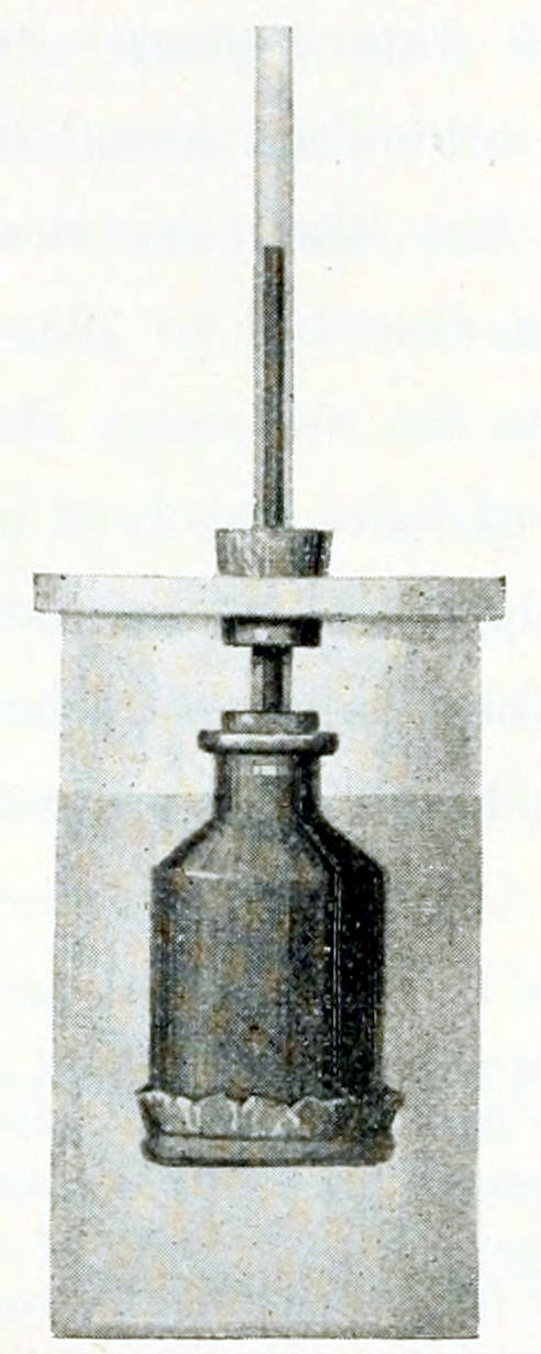 A cylinder standing
vertically, covered with a lid. Through the lid a cork protrudes.
Through the cork extends a thin tube. At the bottom side this tube ends
in a small flask that is hanging in the cylinder. The bottom of the flask
is made of foil, fastened by a thin ring. The cylinder is filled with a
liquid up to a level reaching the neck of the flask. The flask contains
a darker liquid the extends upward through the tube, up to a level above
the lid. The upper border of that liquid is shown.