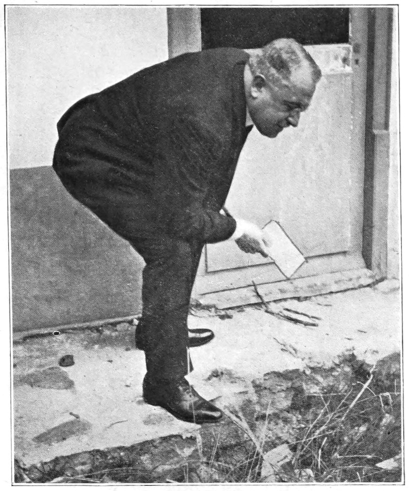 Le Queux bending over examining items on the ground